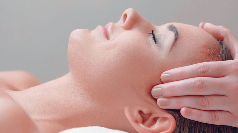 Woman getting her face massaged looking tranquil and peaceful