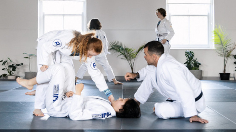 Photo of a jiu-jitsu class with kids and teens on the mat with an instructor
