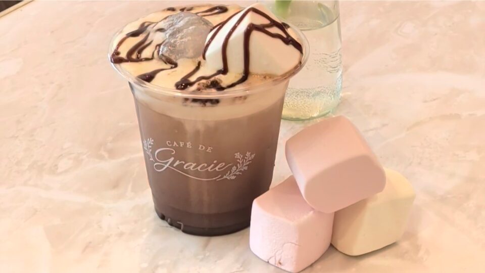 Cup with hot chocolate and marshmallows beside it