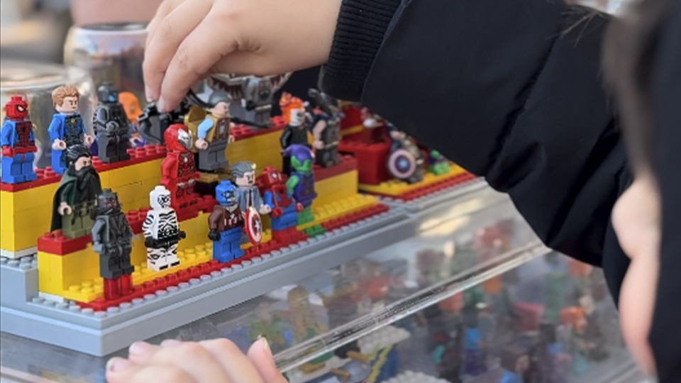 Photo of little boy playing with lego figurines on display at a market stall