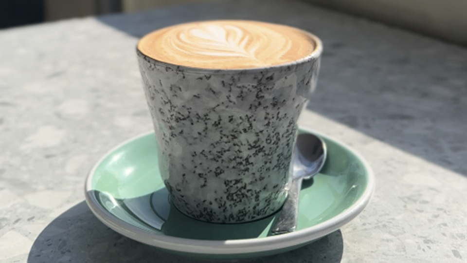Close up shot of a cup of coffee with beautiful latte art in the sunlight