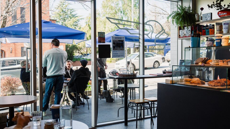 Customer sitting outside a coffee shop with pastries and umbrellas