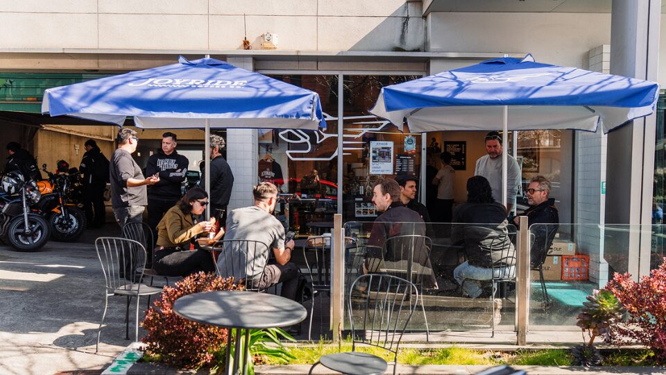 Group of customers sitting out the front of a coffee shop eating toasties